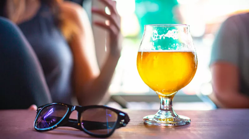 Bicchiere di birra su un tavolo con occhiali da sole in un'atmosfera estiva e rilassata